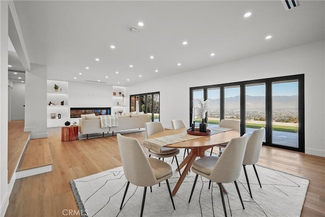 dining area featuring a mountain view, light hardwood / wood-style flooring, and built in features