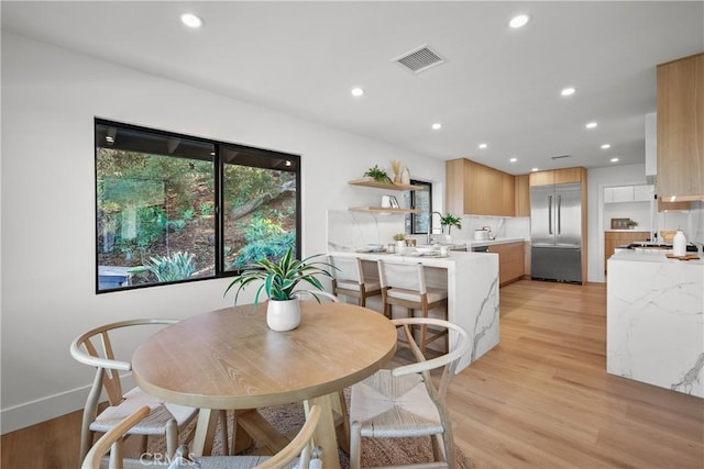 dining space with sink and light hardwood / wood-style floors