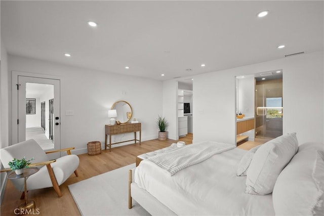 bedroom with connected bathroom and hardwood / wood-style floors