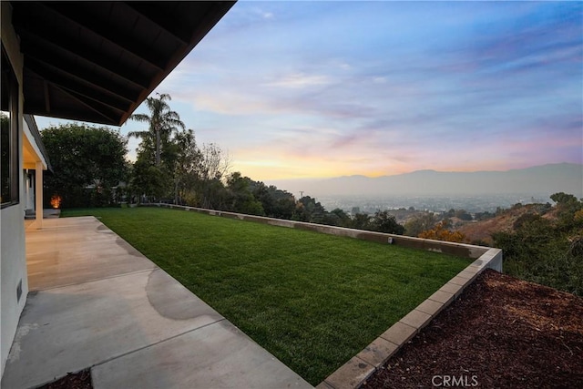 yard at dusk with a patio and a mountain view