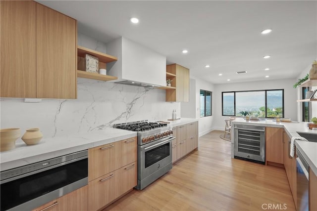 kitchen featuring beverage cooler, decorative backsplash, light hardwood / wood-style floors, stainless steel appliances, and wall chimney range hood