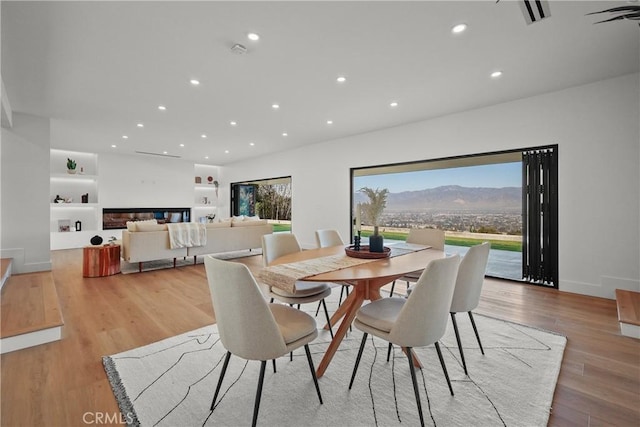 dining space with a mountain view, built in features, and light hardwood / wood-style flooring