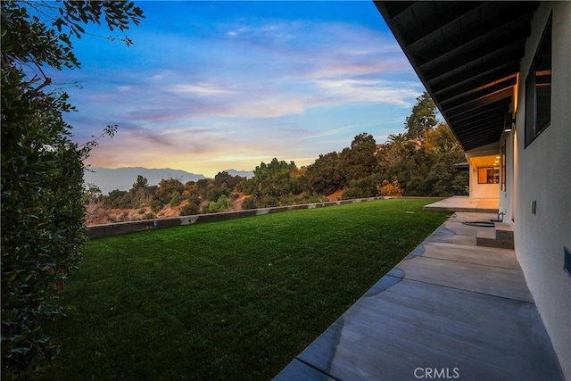 yard at dusk with a patio and a mountain view