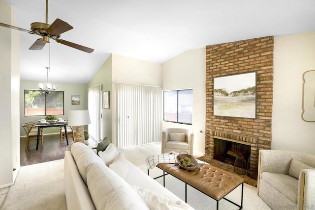 living room featuring light wood-type flooring, a brick fireplace, lofted ceiling, and ceiling fan with notable chandelier