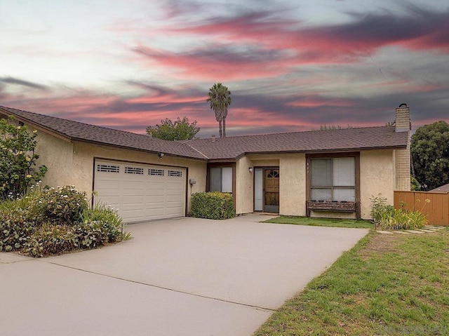 ranch-style home featuring a garage and a lawn