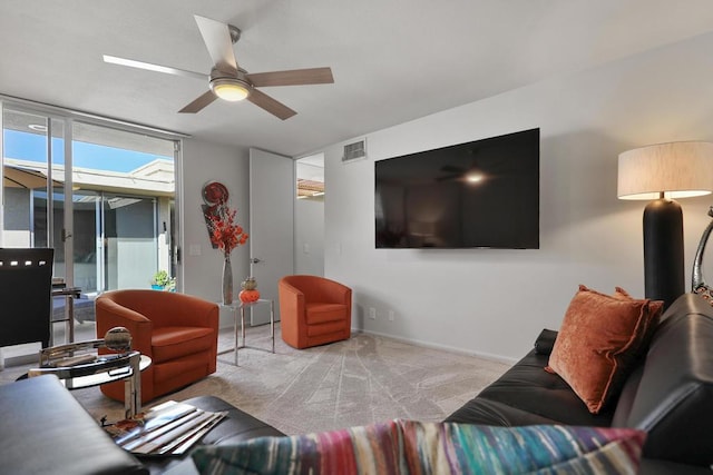 living room with ceiling fan, light colored carpet, and a wall of windows