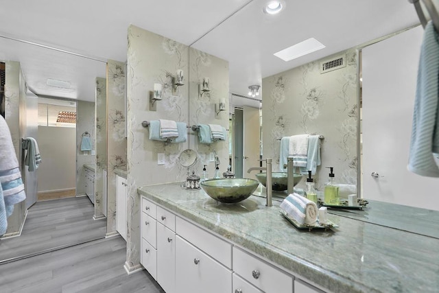 bathroom featuring a skylight, hardwood / wood-style flooring, and vanity