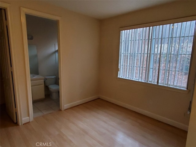 unfurnished bedroom featuring connected bathroom and light hardwood / wood-style flooring