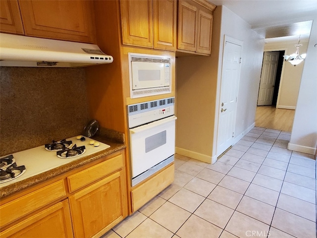 kitchen featuring light tile patterned floors, white appliances, and a chandelier