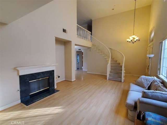 unfurnished living room with hardwood / wood-style flooring, a notable chandelier, and a towering ceiling