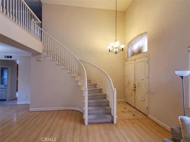 entrance foyer with an inviting chandelier, hardwood / wood-style floors, and a high ceiling