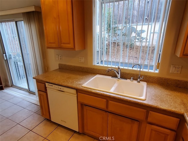 kitchen with light tile patterned floors, white dishwasher, plenty of natural light, and sink