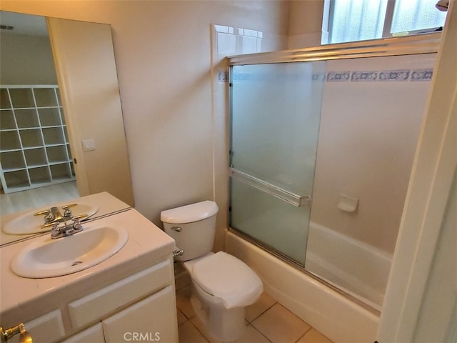 full bathroom featuring toilet, combined bath / shower with glass door, tile patterned floors, and vanity