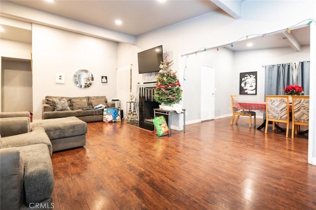 living room featuring dark wood-type flooring, beam ceiling, and a towering ceiling