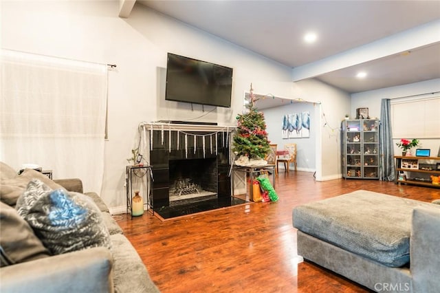 living room featuring beam ceiling, wood-type flooring, and a fireplace