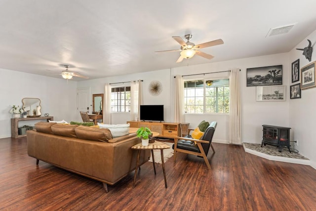 living room featuring ceiling fan, a wood stove, and dark hardwood / wood-style flooring