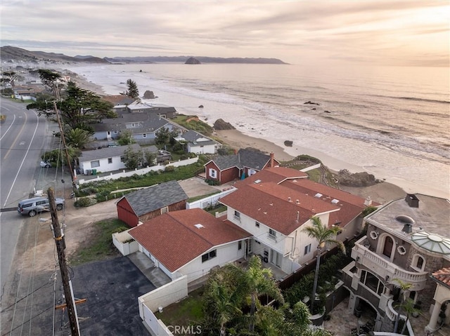 aerial view at dusk with a water view and a beach view