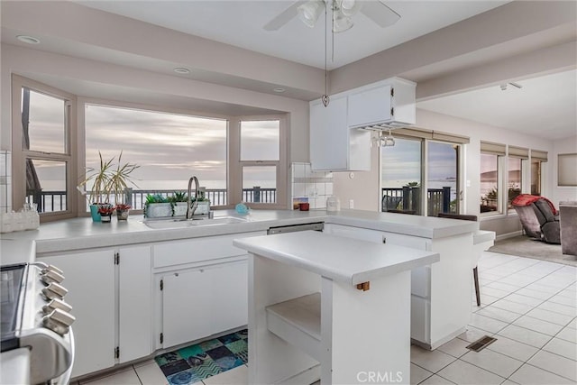 kitchen featuring stove, white cabinetry, kitchen peninsula, and sink