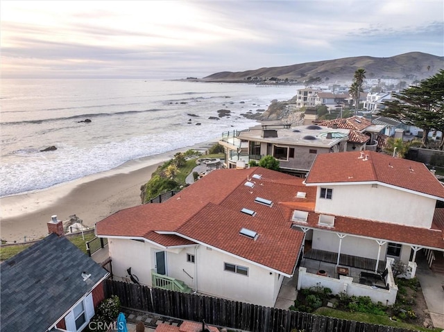 aerial view at dusk with a water and mountain view and a view of the beach