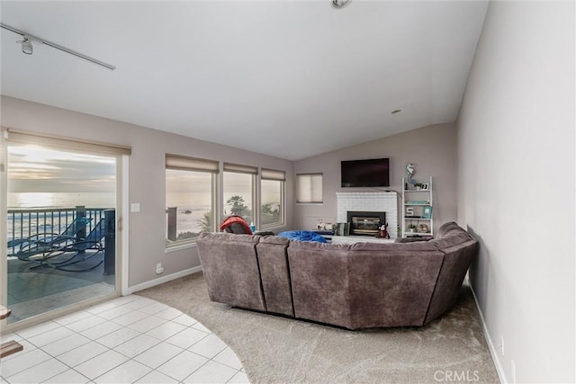 carpeted living room featuring vaulted ceiling, a brick fireplace, and track lighting