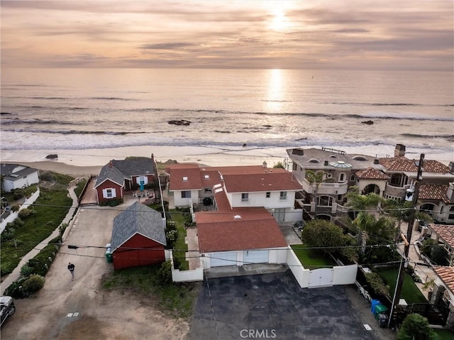 aerial view at dusk featuring a view of the beach and a water view