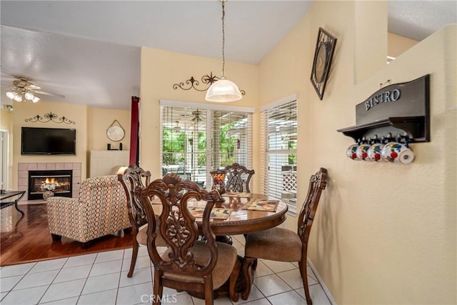 tiled dining room with ceiling fan and a tile fireplace