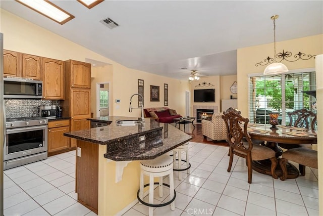 kitchen featuring appliances with stainless steel finishes, backsplash, hanging light fixtures, vaulted ceiling, and sink