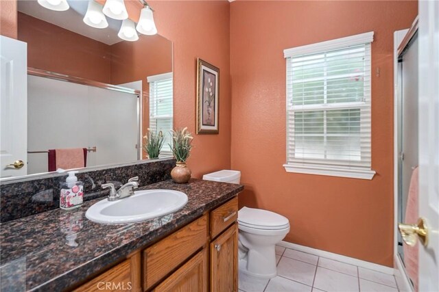 bathroom featuring walk in shower, vanity, tile patterned floors, and toilet