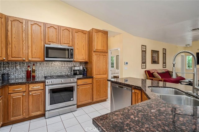 kitchen with light tile patterned floors, stainless steel appliances, decorative backsplash, vaulted ceiling, and sink