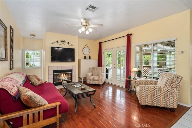 living room featuring ceiling fan, wood-type flooring, french doors, and a tile fireplace