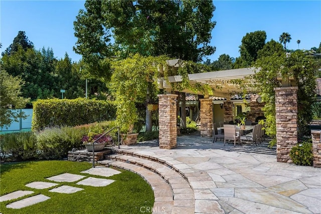 view of patio with an outdoor stone fireplace and a pergola