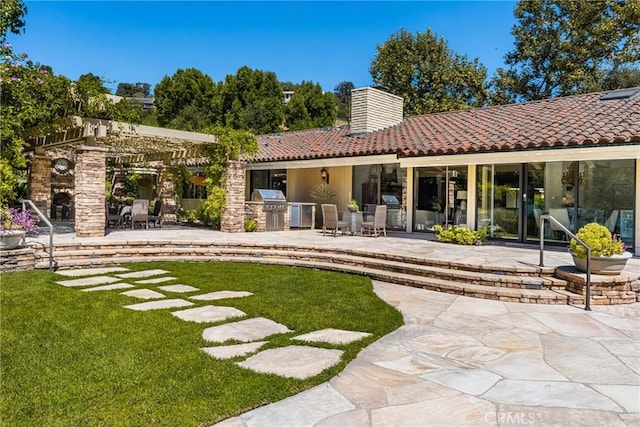 rear view of house with a patio area, a fireplace, and an outdoor kitchen