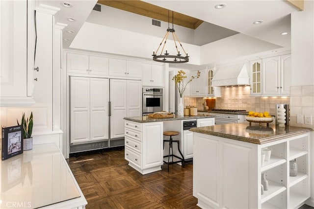 kitchen featuring stainless steel appliances, custom range hood, white cabinets, and a kitchen island