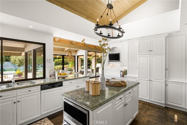 kitchen with white cabinetry, sink, stainless steel microwave, and decorative light fixtures