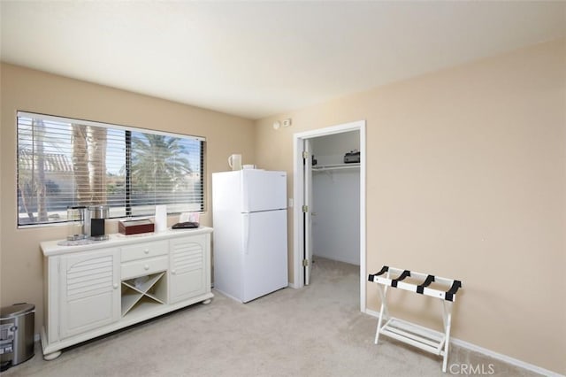 interior space with a walk in closet, a closet, and white fridge