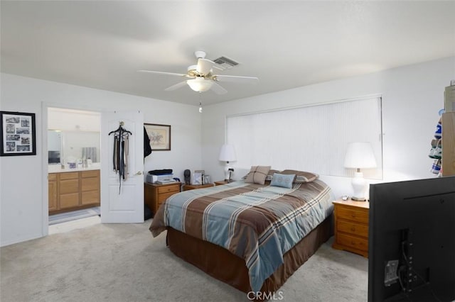 bedroom featuring ceiling fan, light colored carpet, and ensuite bathroom