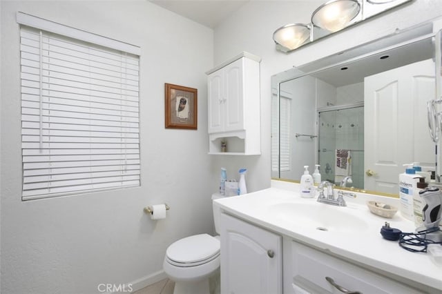 bathroom with vanity, toilet, and a shower with door