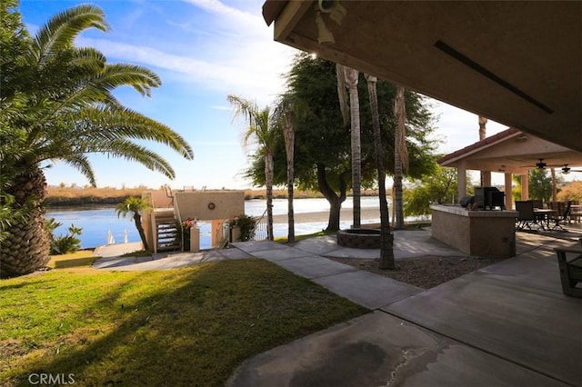 view of home's community featuring a water view, a lawn, and a patio area