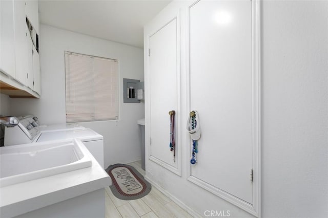 clothes washing area featuring sink, washer and dryer, electric panel, and cabinets