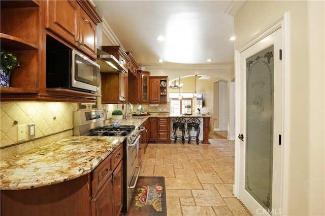 kitchen with backsplash, sink, crown molding, light stone countertops, and stainless steel appliances