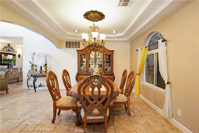 dining space with an inviting chandelier and a raised ceiling