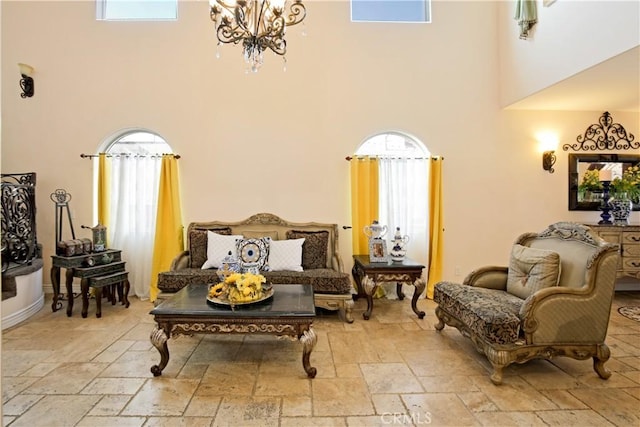 sitting room with a healthy amount of sunlight, a towering ceiling, and a notable chandelier