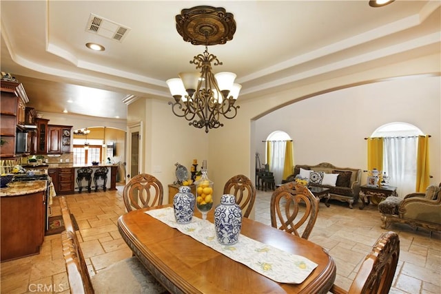 dining space featuring a raised ceiling and a chandelier