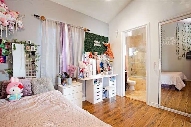 bedroom with ensuite bath, lofted ceiling, and hardwood / wood-style flooring