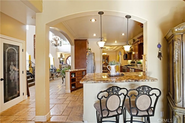 kitchen with light stone countertops, appliances with stainless steel finishes, hanging light fixtures, kitchen peninsula, and crown molding