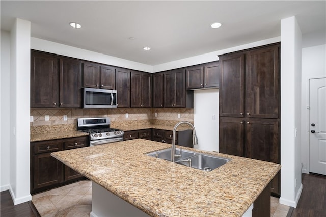 kitchen featuring sink, dark brown cabinetry, stainless steel appliances, and a kitchen island with sink