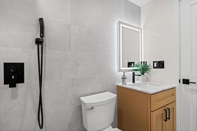 bathroom with tile walls, toilet, and vanity