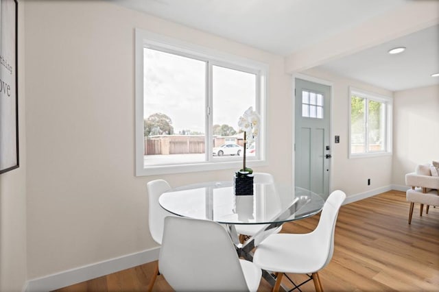 dining space with beam ceiling and light hardwood / wood-style floors