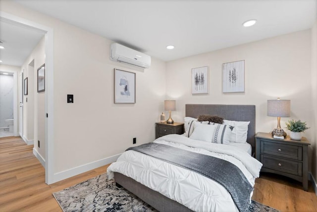 bedroom with an AC wall unit and light hardwood / wood-style floors