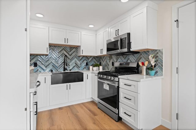 kitchen with appliances with stainless steel finishes, backsplash, white cabinetry, and sink